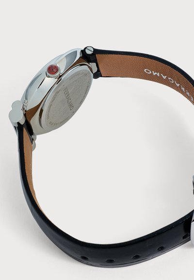 Ασημένιο ρολόι Ferragamo με καφέ δερμάτινο λουράκι και κόκκινη λεπτομέρεια στην κορώνα, σε πλευρική όψη που δείχνει το πίσω μέρος της κάσας και το εσωτερικό του λουριού.