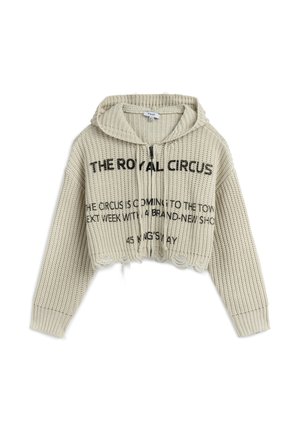 Geknipte beige gebreide hoodie met een textuur, capuchon met trekkoord en zwarte opdruk op de voorkant. Heeft een gegolfde zoom.