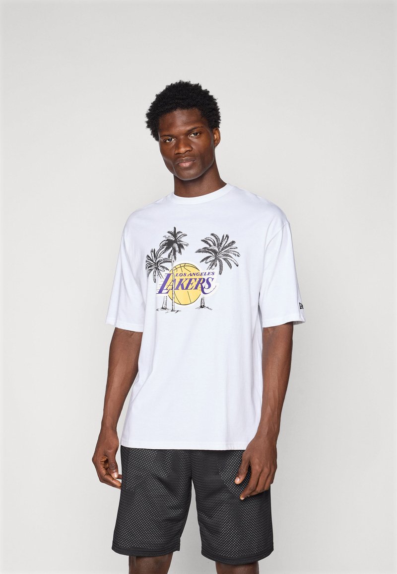 Biela tričko s krátkym rukávom s grafikou paliem a textom "Los Angeles Lakers" v purpurovej farbe, doplnené čiernymi sieťovanými šortkami.