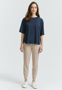 Top de manga corta en color azul marino combinado con pantalones tapered beige y zapatillas blancas. El top tiene un corte relajado y un escote redondo.