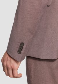 Brązowa teksturowana rękaw marynarki z czterema ciemnymi guzikami i detalami szycia. Widoczny subtelny połysk i dopasowany krój.