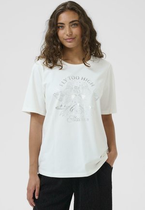 T-shirt blanc à manches courtes en tissu doux, avec un design graphique argenté représentant des oiseaux et le texte "FLY TOO HIGH" et "Liberté."