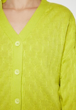 Limettengrüner Strickcardigan mit V-Ausschnitt, der ein strukturiertes Muster aufweist und drei runde, hellgrüne Knöpfe auf der Vorderseite hat.