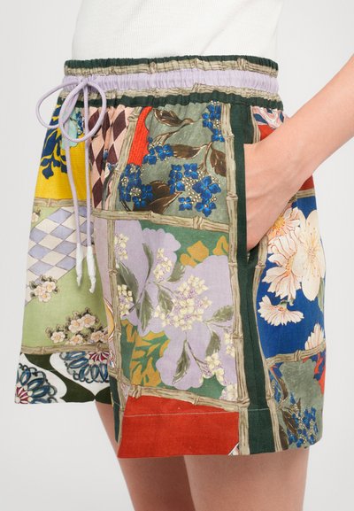 Colorful patchwork shorts made of fabric featuring floral and geometric prints. Elastic waistband with drawstring, side pockets visible.