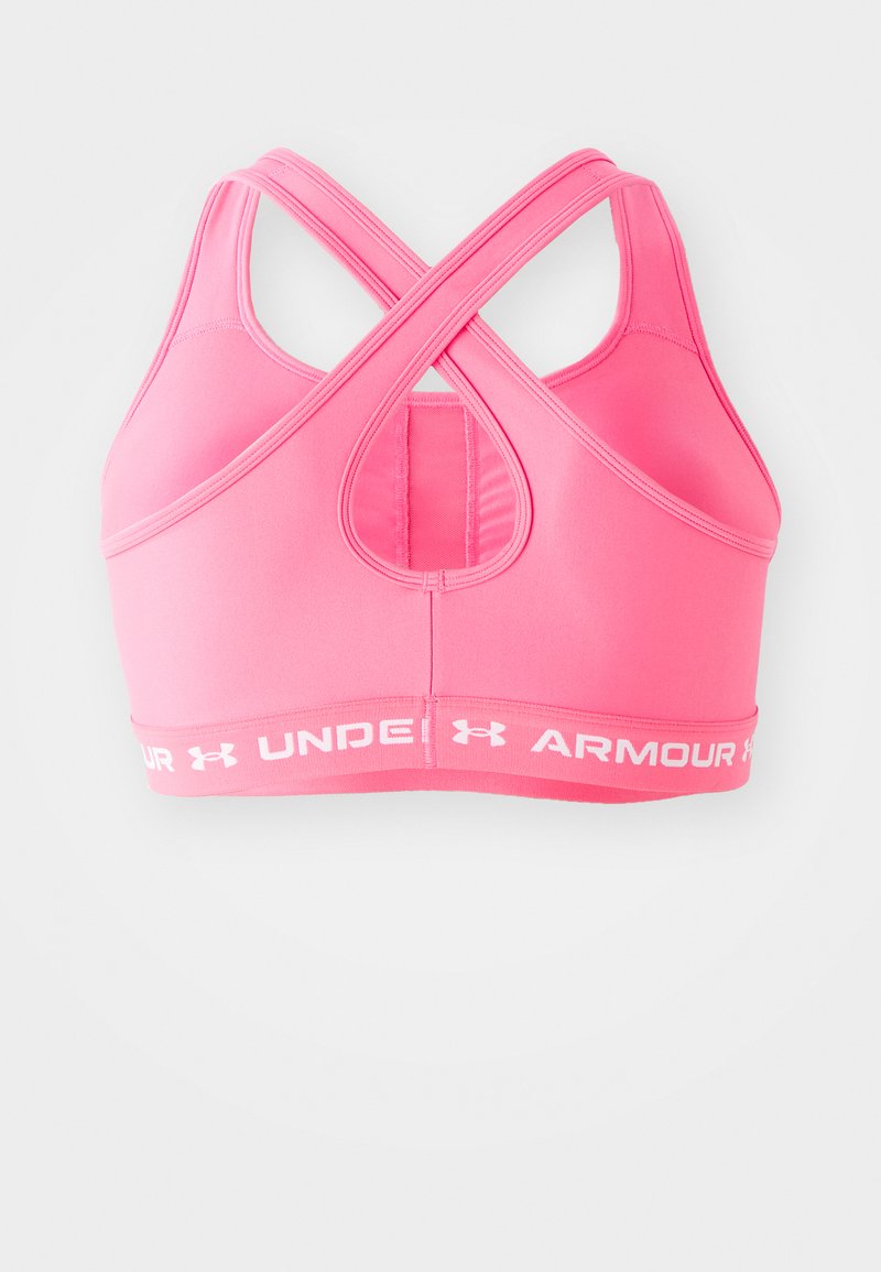 Reggiseno sportivo rosa con design incrociato sulla schiena, realizzato in materiale elasticizzato. Presenta un bordo con logo bianco nella parte inferiore e un pannello in rete sul retro.
