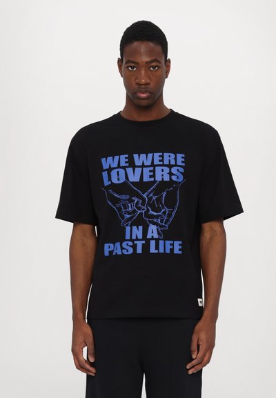 Schwarzes Baumwoll-T-Shirt mit kurzen Ärmeln und rundem Halsausschnitt, mit blauer Schrift und grafischen Händen auf der Vorderseite bedruckt.