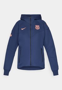 Navy zip-up sweatshirt with a hood, featuring a pink Nike logo and Barcelona team crest. Includes two side pockets and ribbed cuffs.