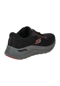 Sneaker nera con tomaia in rete, suola intermedia grigia, accenti rossi e marchio 'ArchFit'. Presenta un collare imbottito e suola in gomma per una buona trazione.