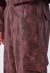 Cargo shorts in een diep bordeauxrode stof, met een gestructureerd oppervlak, zijzakken en een patch met reliëf logo-detail.
