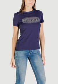 T-shirt in cotone color blu navy con maniche corte e colletto rotondo, caratterizzato da "GUESS" in scintillanti strass sul petto.