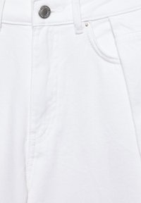 Weiße Denim-Jeans in Nahaufnahme mit Bund, Knopf, Reißverschlussbereich und Vordertasche mit Nieten-Detail.