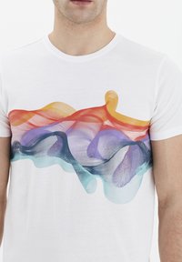 Camiseta de algodón blanca con un colorido patrón abstracto de olas en rojo, naranja, púrpura y verde azulado en el pecho. Mangas cortas, cuello redondo.