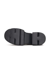 Suola nera delle scarpe con un design piatto, caratterizzata da sezioni rialzate e scanalature per la trazione. Realizzata in gomma, con una finitura liscia.