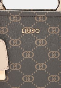 Grijze gestructureerde handtas met gouden signatuur 'LIU•JO' en een patroon van in elkaar grijpende logo's, voorzien van een beige accent en gladde hardware.