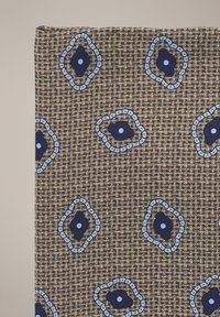 Tkanina o brązowej, plecionej fakturze z powtarzającym się niebieskim i granatowym wzorem kwiatowym obrysowanym jasnym niebieskim.