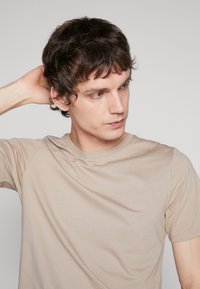 Beige short-sleeve t-shirt made of soft cotton material, featuring a crew neckline and minimalistic design without patterns or accents.