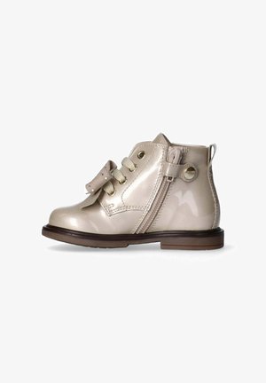 Beige laarzen van patenterleer tot de enkel met een ronde neus, vetersluiting aan de voorkant, decoratieve strik en een zijrits voor gemakkelijk aantrekken. Bruine rubberen zool.