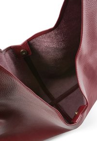 Sac à main en cuir bordeaux profond avec un extérieur texturé, un dessus ouvert et une poche intérieure. Doublure douce type daim avec fermeture à pression magnétique.
