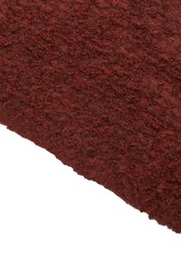 Tessuto rosso testurizzato, caratterizzato da una superficie morbida e soffice. Il materiale ha una tonalità calda e ricca con variazioni di tono.