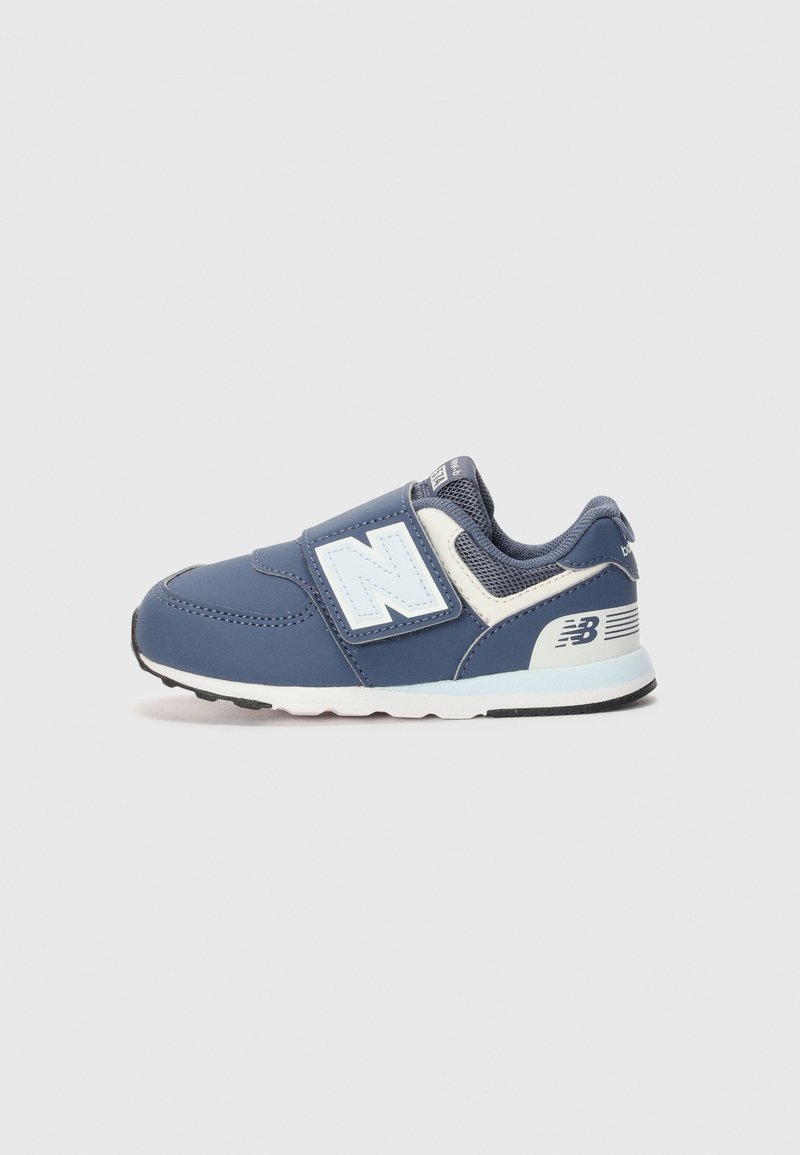 Zapatilla deportiva azul con una correa de velcro que presenta un logo blanco. El material es sintético con una superficie texturizada y suela de goma.