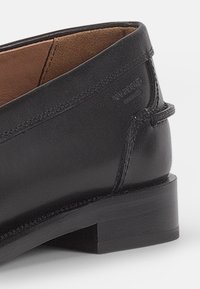 Svart läderankelsk boot med låg blockklack, slät yta, subtil sömnad och brun inre foder. Har präglad logotypdetalj.