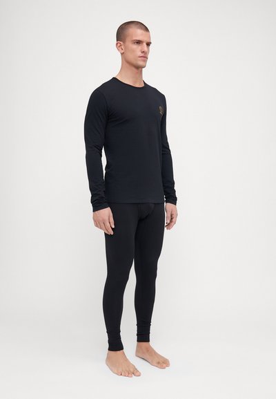 Svart långärmad tröja och leggings i stretchmaterial, figurnära design, med en liten logotyp på bröstet, slät textur och utan mönster.