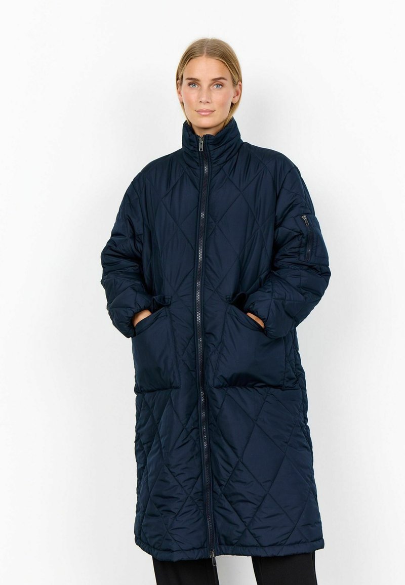 Marineblå quiltet pufferjakke med høj krave, for-zip og to sidelommer. Har diamantmønster og oversize-design.