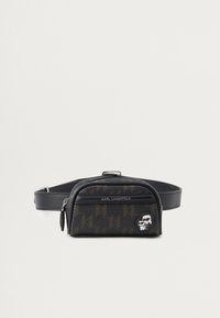 Czarna skórzana torba na pasek z monogramowym wzorem, zamykanymi komorami oraz charakterystycznym akcentem loga Karla Lagerfelda z rysunkową twarzą.