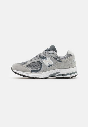 Grauer und dunkelgrauer New Balance 2002R Sneaker mit Mesh- und Veloursleder-Overlays, weißer Zwischensohle und schwarzer Gummiaußensohle, von der Seite gezeigt.