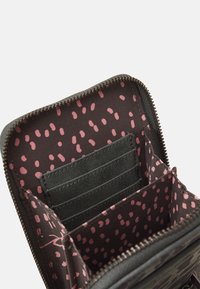 Czarny portfel z różowymi kropkami w środku, z wieloma kieszonkami na karty i centralną przegrodą, zamykany na zamek.