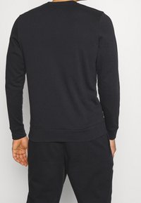 Felpa nera a maniche lunghe, realizzata in misto cotone, con scollo rotondo e polsini a costine, in un colore unico e design casual.