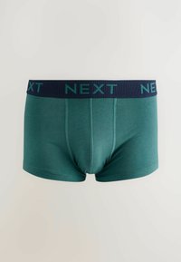 Gröna boxershorts med ett marinblått elastiskt midjeband som har "NEXT" i ljusblå bokstäver, tillverkade av ett mjukt och elastiskt material.