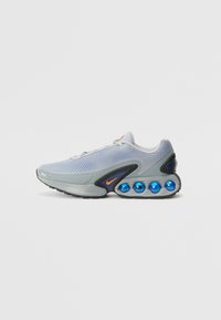Light gray sneaker with a mesh upper, orange logo, black accents, and distinctive blue cushioning pods on the sole. Rounded toe design.