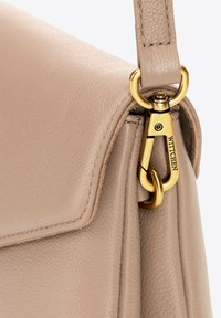 Beige kožená kabelka s hladkým povrchem, vyznačující se zlatým kováním a švy na okrajích. Viditelné jméno značky.