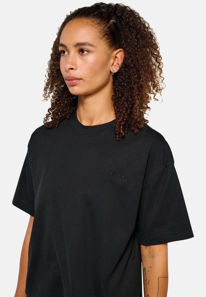 Svart kortärmad t-shirt i bomull, med ett präglat "HALO"-logotyp på bröstet, avslappnad passform och rund halsringning.