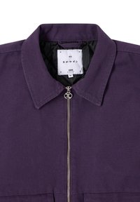 Giacca con zip viola caratterizzata da un colletto a punta, hardware argentato e un tessuto testurizzato. L'etichetta interna mostra il nome del marchio e la taglia (M).