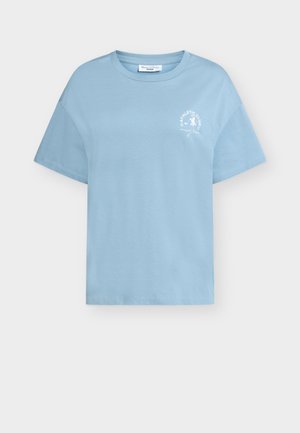 Lys blå T-skjorte med korte ermer, med en liten hvit "Athletic Club"-grafikk og en løpende figur på venstre bryst.