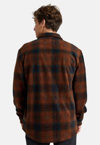 Braune und blaue karierte Flanellhemd, lange Ärmel, geknöpfte Manschetten, Kragen, strukturierter Stoff, leicht abgerundeter Saum, sichtbare Nähdetails.