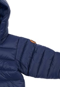 Navy pufferjack met een close-up van de quiltstructuur, capuchon en een ronde logopatch op de schouder. Glad, lichtgewicht materiaal.