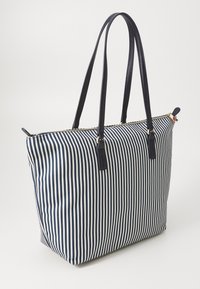 Sac fourre-tout rayé avec des rayures verticales bleues marine et blanches, en tissu, avec deux poignées en cuir noir et des détails en fermeture éclair dorée.