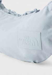 Τσαντάκι ώμου από ανοιχτό γαλάζιο ύφασμα με ρυθμιζόμενο κορδόνι σύσφιξης και ανάγλυφο ορθογώνιο λογότυπο μπροστά.