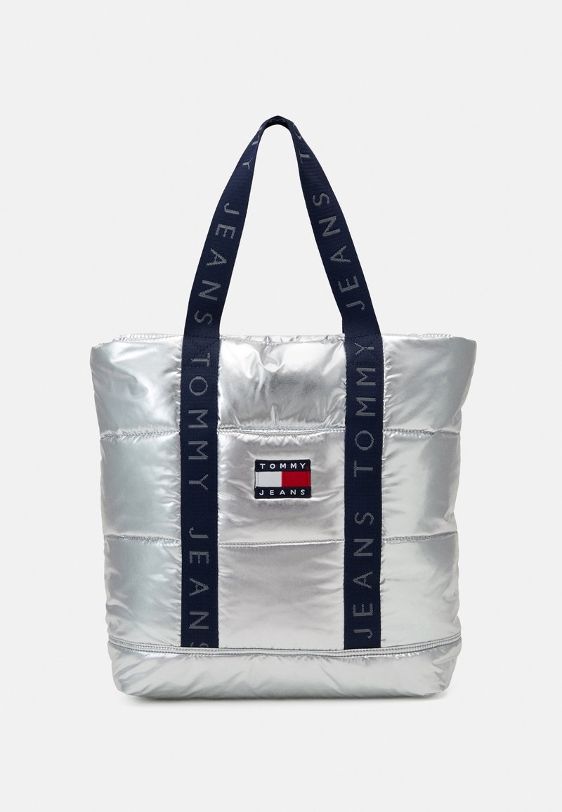 Sac cabas matelassé argenté avec anses bleu marine portant le texte « Tommy Jeans » et un patch logo rectangulaire Tommy Jeans à l'avant.