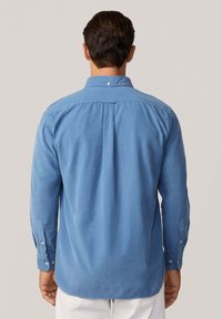Lichtblauwe overhemd met lange mouwen, een button-down kraag, gestructureerde stof en met knopen afgewerkte manchetten. Gladde afwerking met een rechte onderkant.