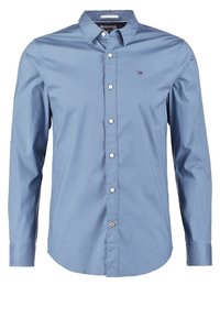 Chemise homme bleu clair à manches longues, boutonnée, avec col et petit logo Tommy Hilfiger sur la poitrine.