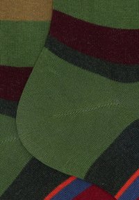 Calzini a maglia verdi con strisce orizzontali in rosso scuro, nero, blu, arancio e marrone, che mostrano le aree del tallone e della caviglia.