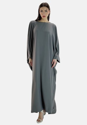Graues Kaftan-Kleid mit langen Ärmeln, lockerer Passform und glatter Textur. Mit Rundhalsausschnitt und Seitentaschen. Getragen mit weißen Sandalen.
