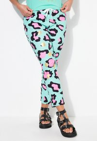 Lightweight mint pants featuring a bold black, pink, and gold leopard print pattern. Finished with a drawstring waist and tapered design.