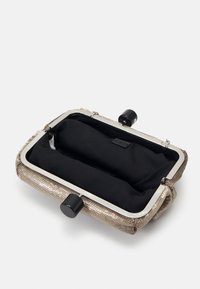 Metaliczna torebka kopertowa z siatki o złotym odcieniu, z czarnym materiałowym wnętrzem, zaokrąglonym czarnym okuciem i usztywnioną metalową ramą.