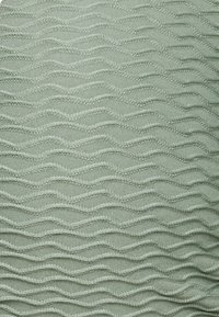 Um tecido texturizado numa suave e suave tonalidade de verde apresenta um padrão ondulante com costura elevada, oferecendo uma aparência tátil e em camadas.