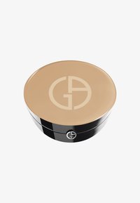 Foundation compact med et blankt beige lokk, med en stor merkevarelogo i sentrum. Basen er slank svart med en jevn tekstur.